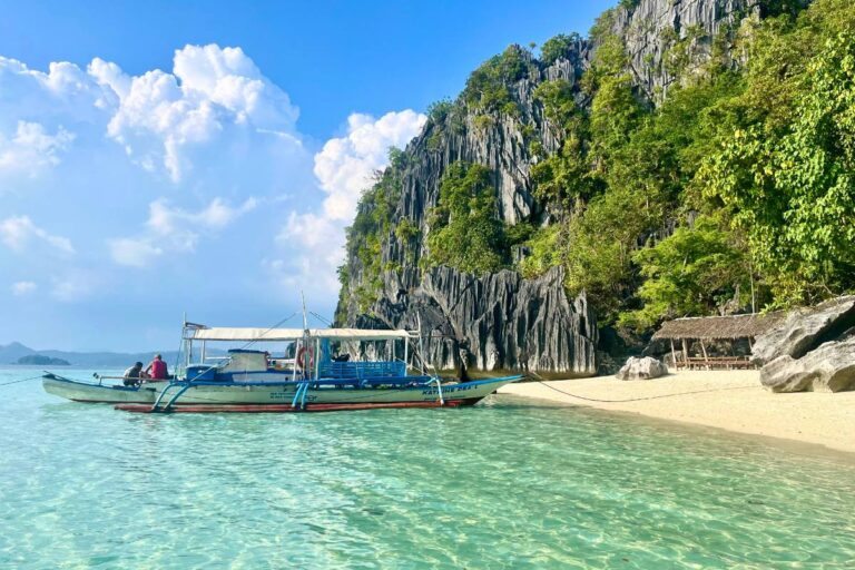 A local boat docked along the shore of a rock island.