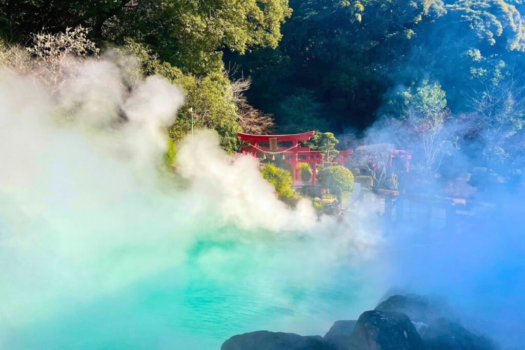 A steamy blue-green onsen with red torii gates in the background