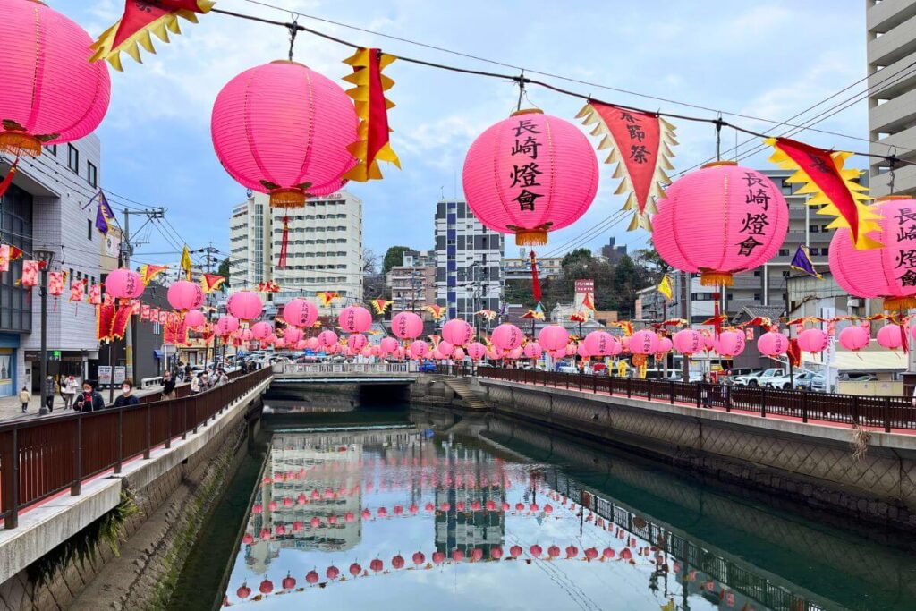 A river in Nagasaki City decorated with bright pink lanterns.