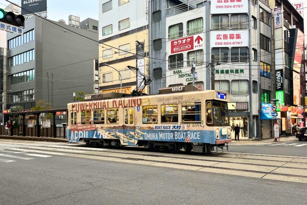 Nagasaki Tram A tan tram driving through downtown Nagasaki