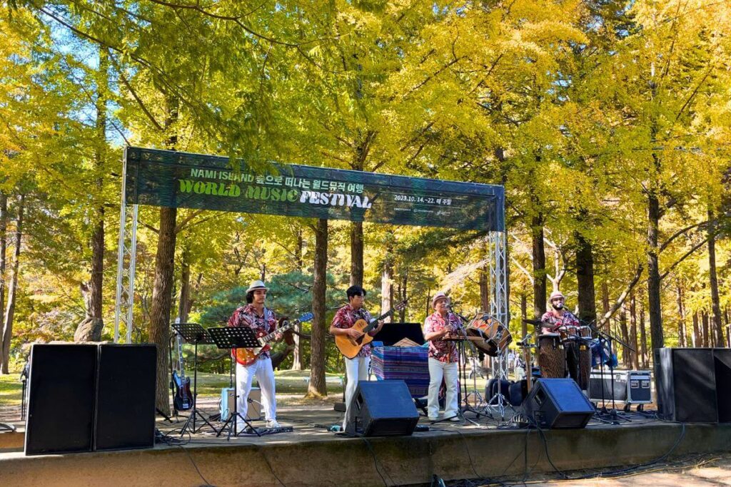 Music Festival Nami Island Autumn Local performers playing outside at the Nami Island World Music Festival with autumn foliage in the background.