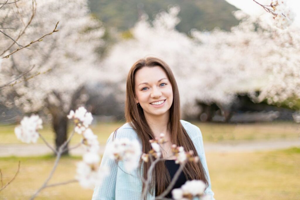 Krysti Iwakuni Cherry Blossoms Krysti smiling in front of cherry blossoms in Iwakuni, Japan.