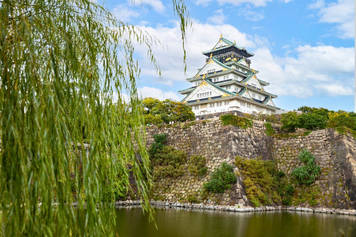 Osaka Castle and moat framed by lush greenery.
