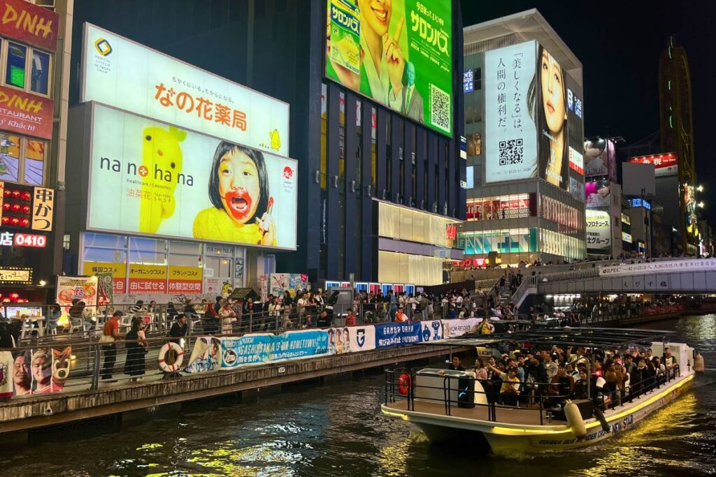 Osaka at Night A view of Dotonbori River lit up at night with a tourist boat driving by.