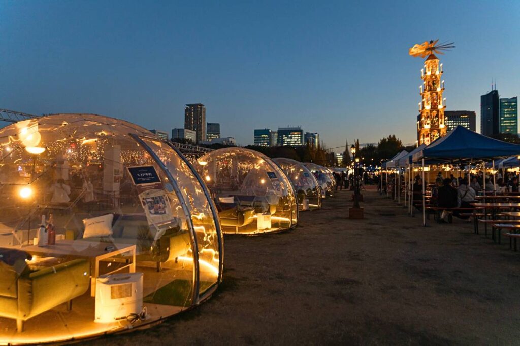 VIP seating at the Tokyo Christmas Market with the tall wooden Christmas pyramid lit up in the background.