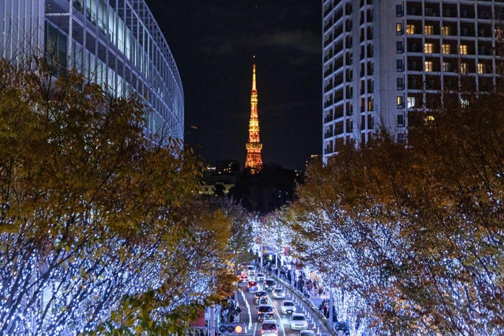Street lined with Christmas trees framing Tokyo Tower lit up at night.