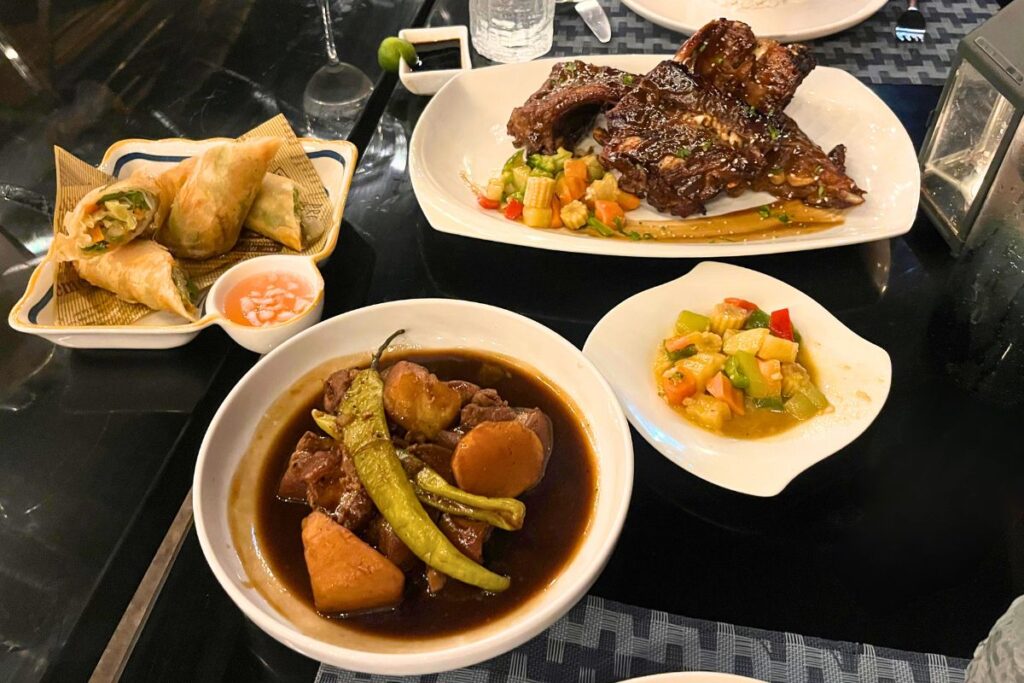 Filipino Food - Coron A table covered with Filipino food - including pork adobo, lumpia, grilled pork ribs, and veggies.