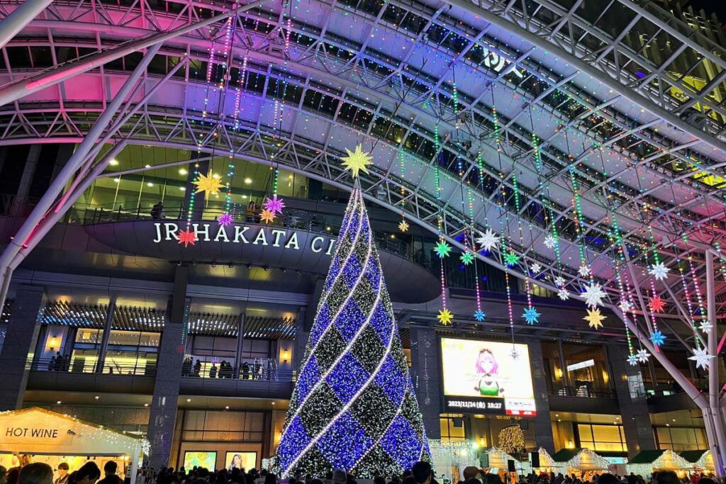 Hakata Fukuoka Christmas Market in Japan JR Hakata Train Station decorated with Christmas lights and a large Christmas tree out front.