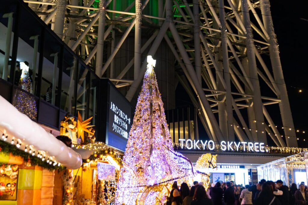 A Christmas tree lit up next to the Tokyo Skytree sign.