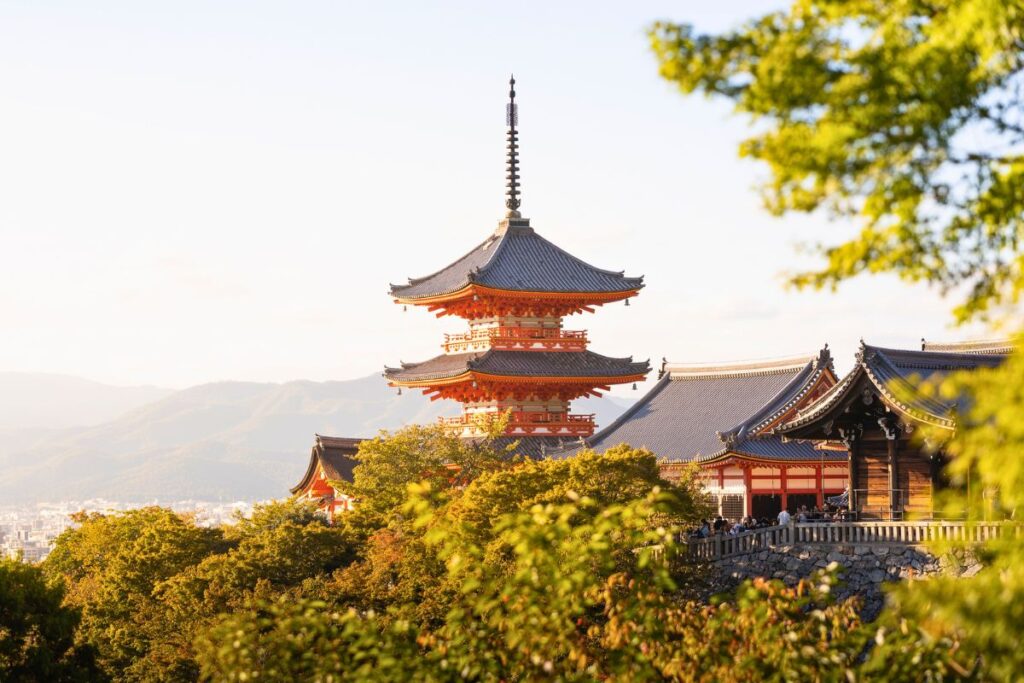 Bright red pagoda framed by greenery with mountains in the background