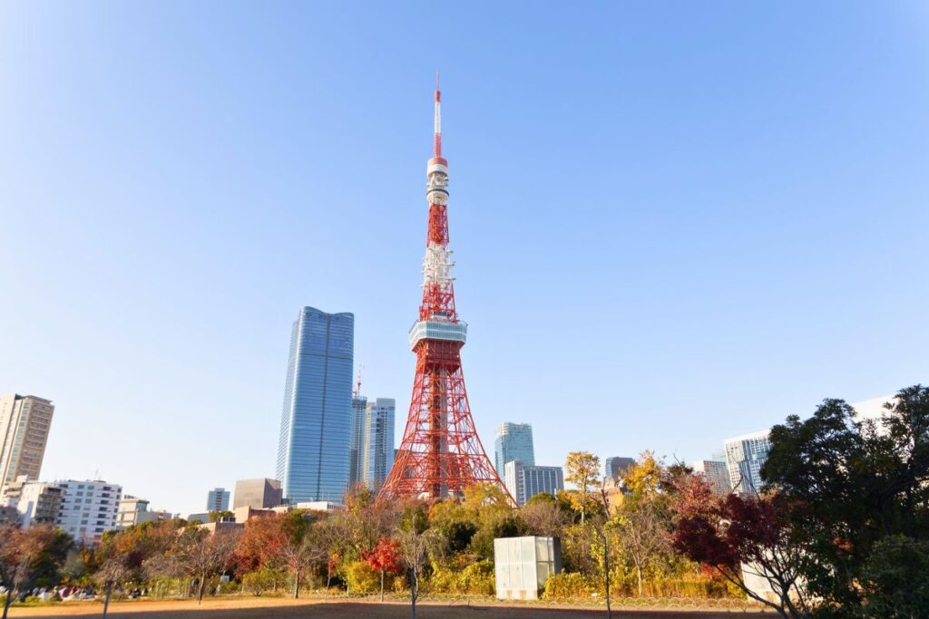 Tokyo Tower with fall trees below and skyscrapers in the background.