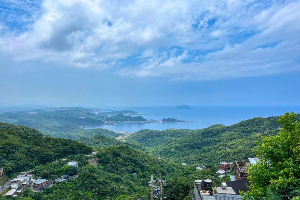 View overlooking Jiufen's coastline with green hills and blue ocean water beyond it.