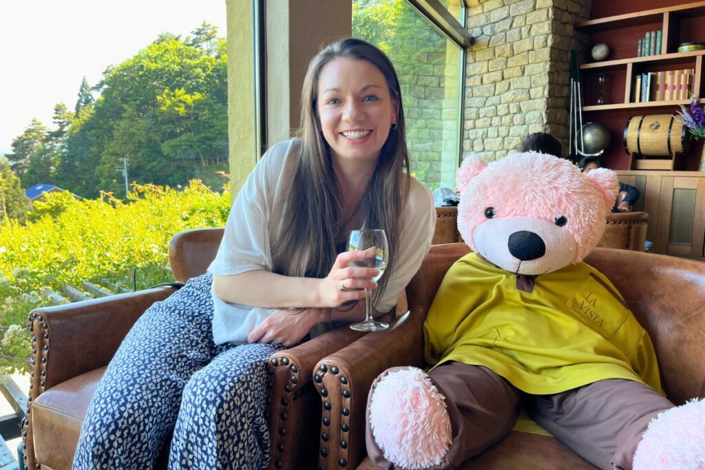 Krysti sitting next to the hotel's mascot - a large, bright pink teddy bear.