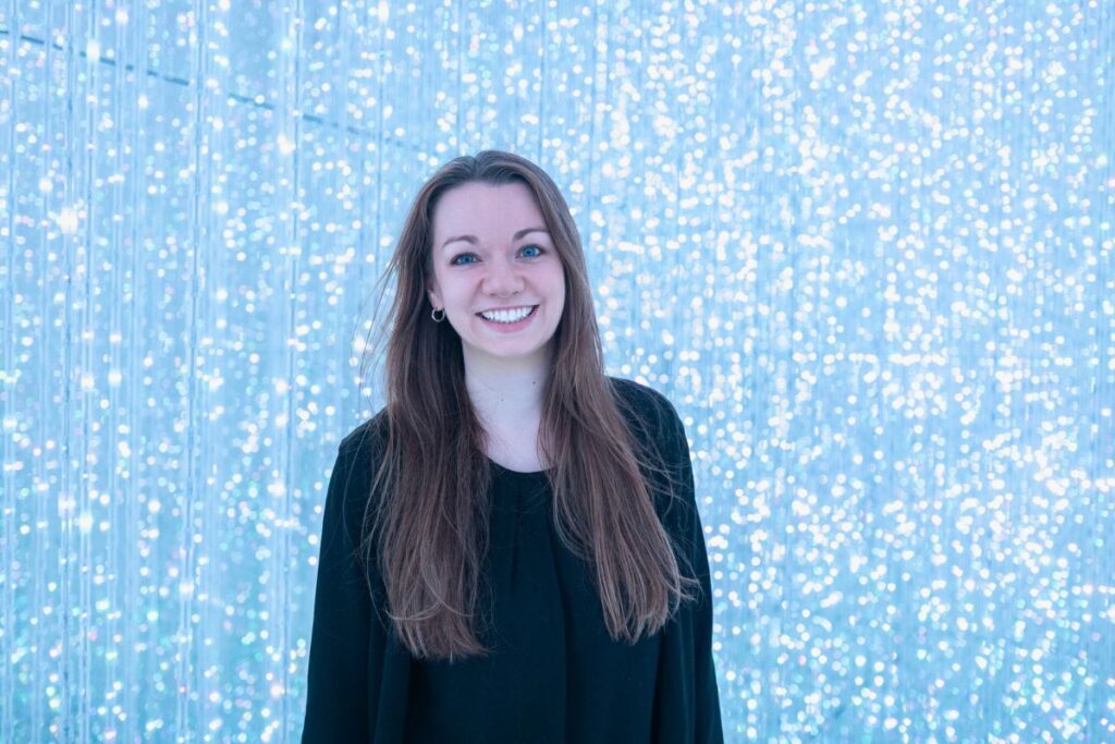 Krysti standing in front of a wall of crystal lights