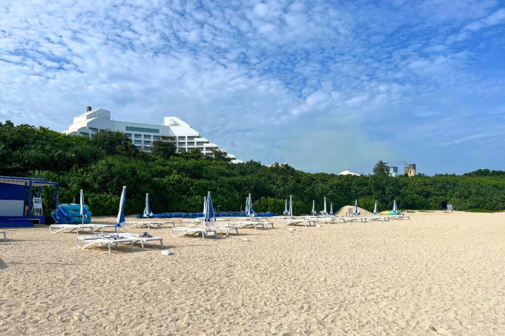 A photo of Maesato Beach lined with sun chairs. You can the top of ANA InterContinental Ishigaki in the background peeking up over the tree line.