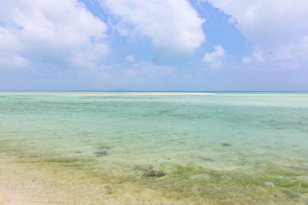 Blue-green waters surrounding a white sandbar.