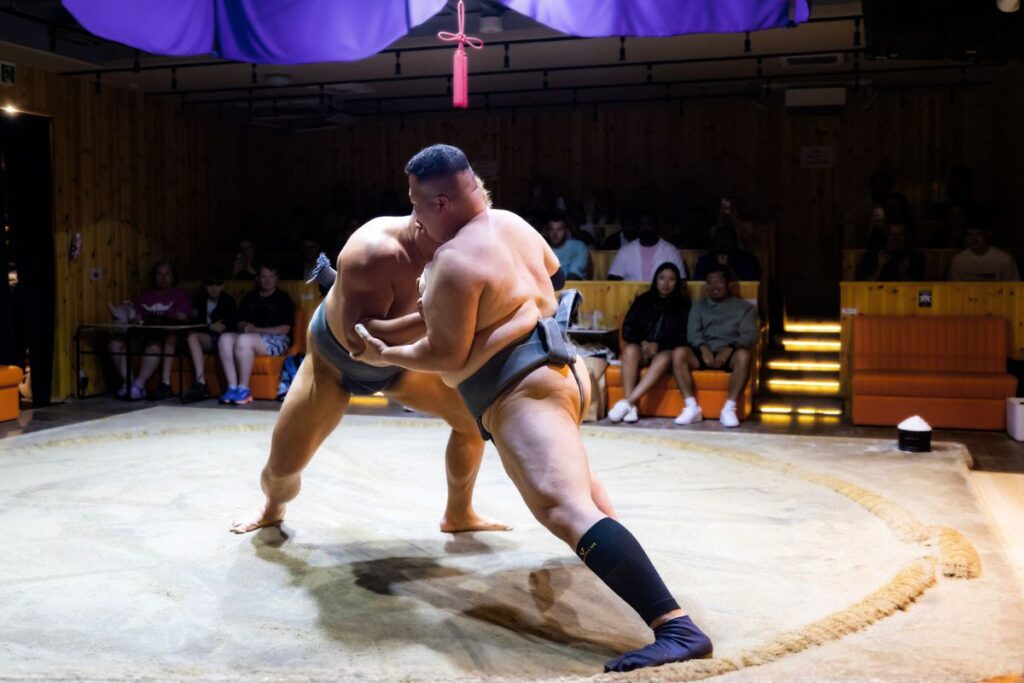 Two sumo wrestlers going head to head at the Asakusa Sumo Club.
